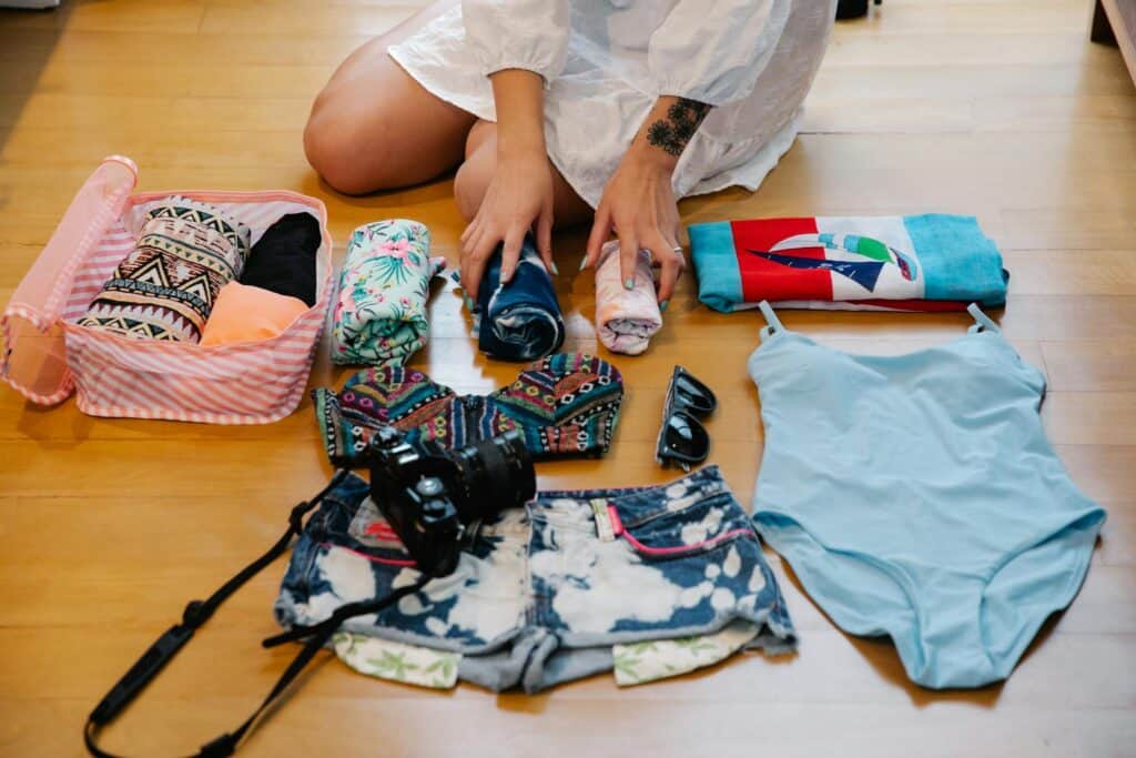 A Person Sitting on a Wooden Floor while Preparing Travel Essentials - miami packing list
