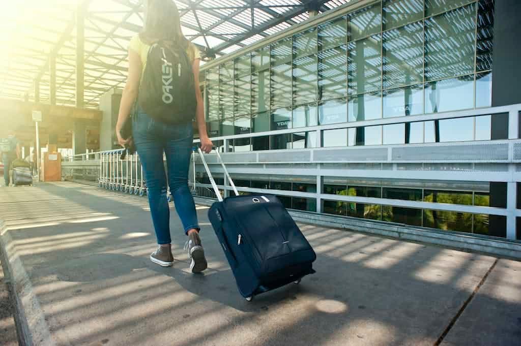 Woman Walking on Pathway While Strolling with carry-on Luggage